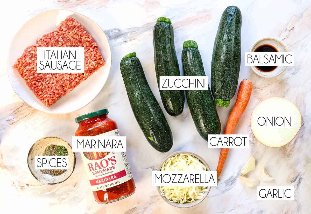 top view of zucchini boats ingredients: zucchini, Italian sausage, marinara sauce, onion, carrots, spices, garlic, mozzarella
