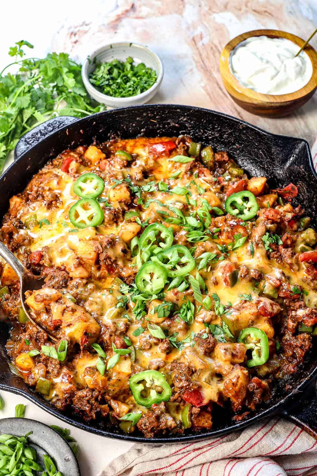 ground beef and potatoes recipe in a skillet showing how cheesy it is