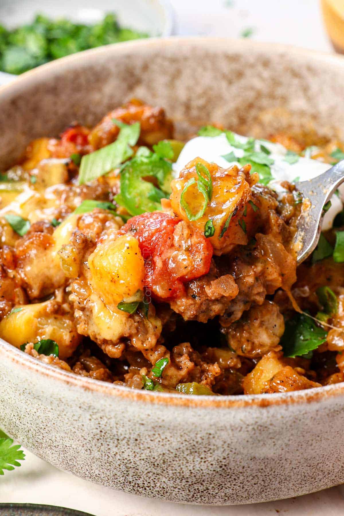 up close of a spoonful of ground beef with potatoes showing how juicy the beef is and how crispy and charred yet tender the potatoes are
