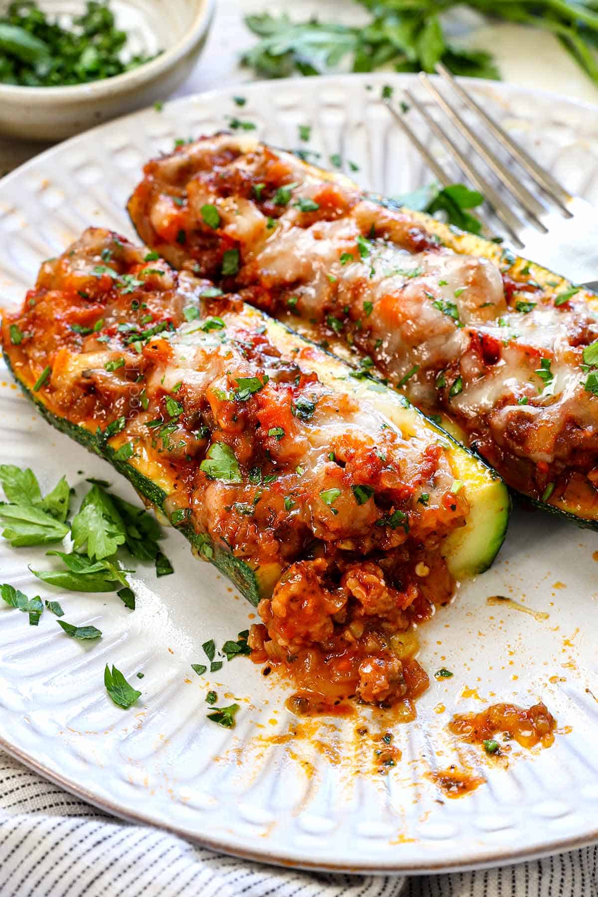 taking a bite out of a zucchini boat showing the crisp-tender texture of the zucchini and the juicy, cheesy sausage filling