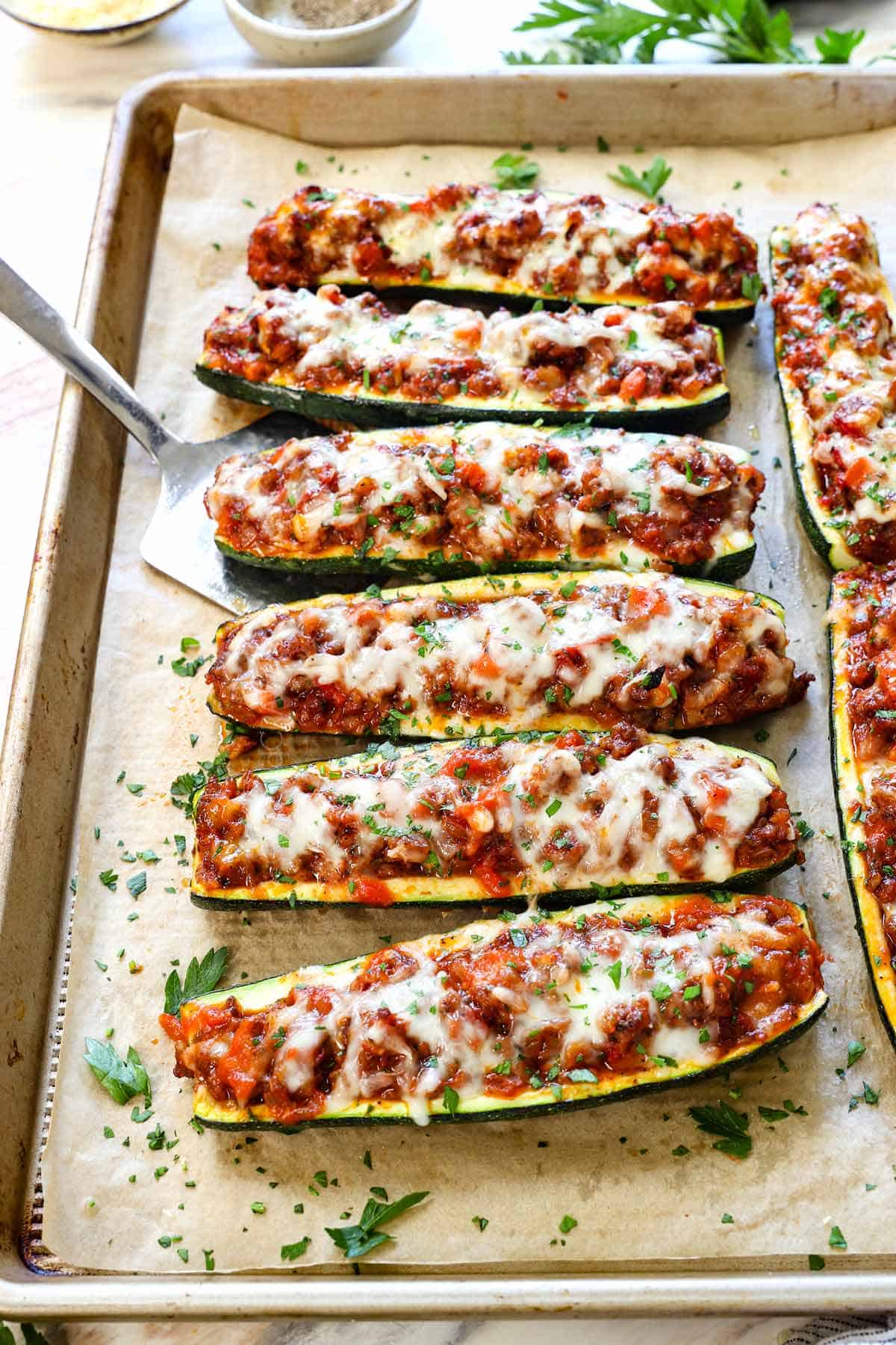 zucchini boat recipe lined on a baking sheet garnished with parsley