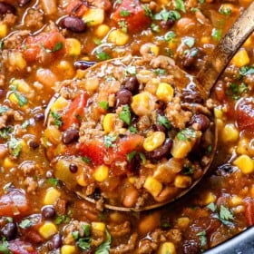 up close of a scoop of slow cooker taco soup showing the ground beef, beans corn, tomatoes