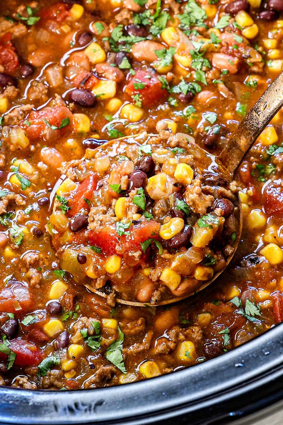 up close of a scoop of slow cooker taco soup showing the ground beef, beans corn, tomatoes