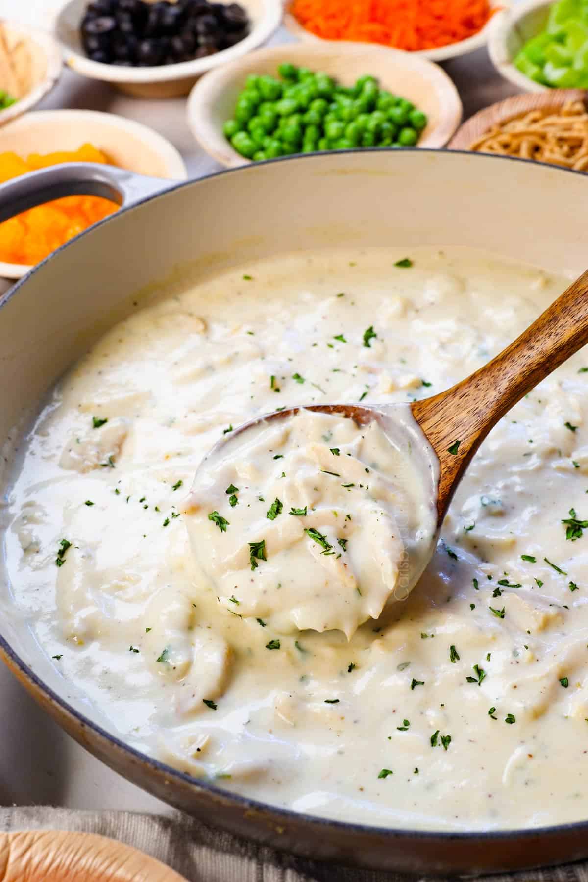 up close of a ladleful of cream of chicken soup with chicken added to it