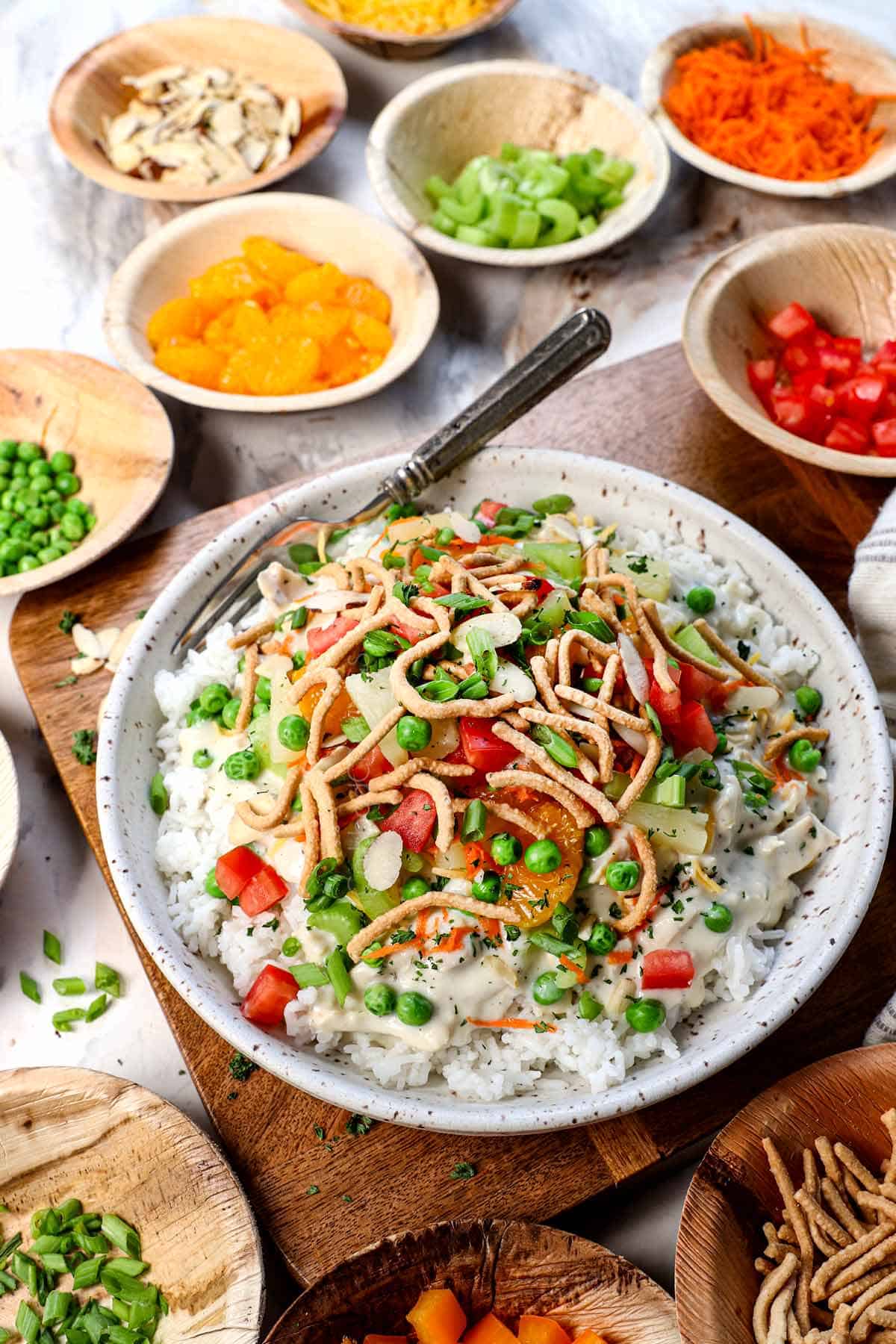 Serving Hawaiian Haystacks in a bowl with toppings, surrounded by bowls of toppings