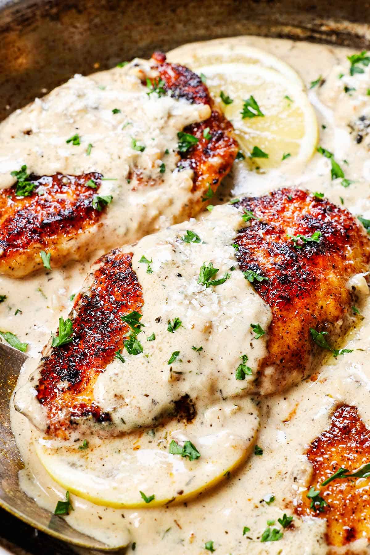 showing how to make lemon chicken by spooning the sauce over the chicken in the skillet