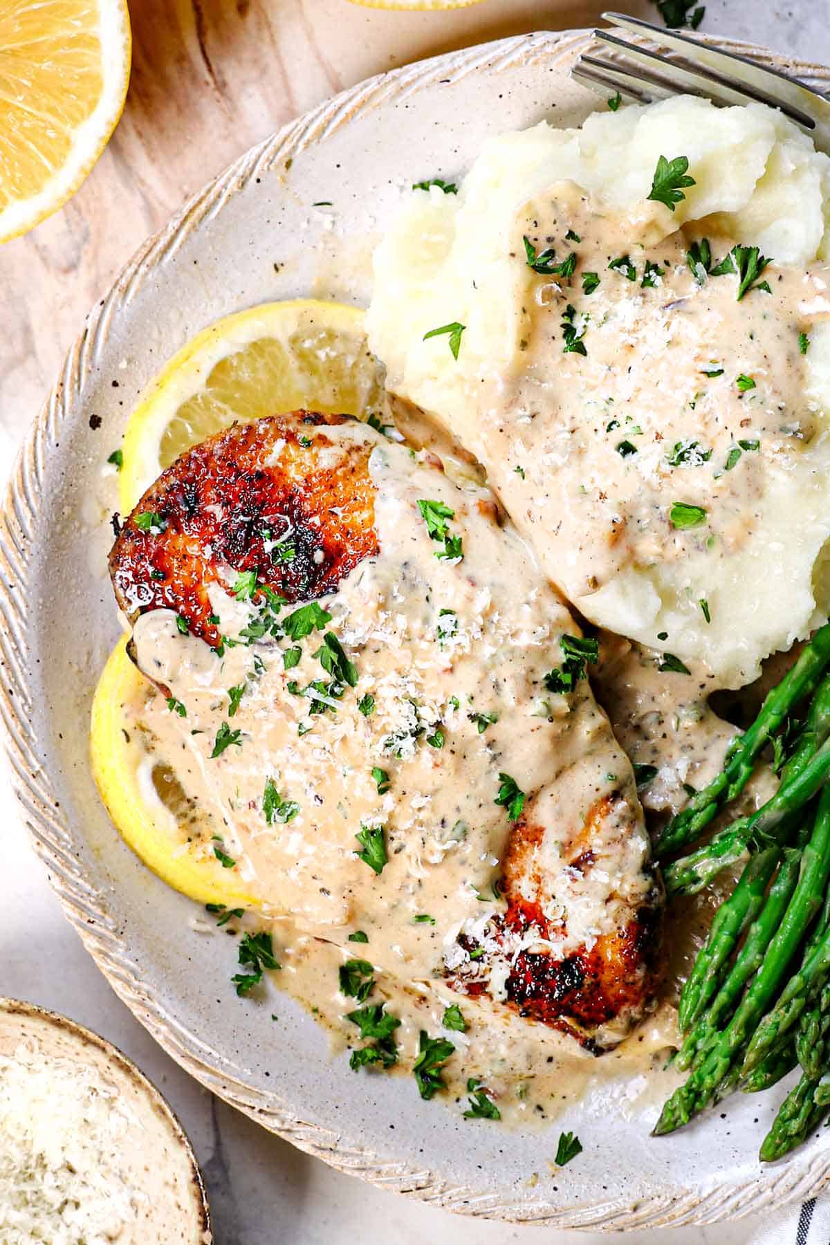 top view showing how to serve creamy lemon chicken with mashed potatoes and asparagus with the creamy sauce spooned over the top