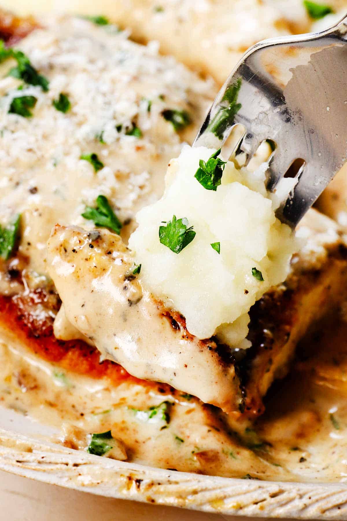 up close of a bite of lemon chicken with sauce and creamy mashed potatoes, showing how juicy the chicken is