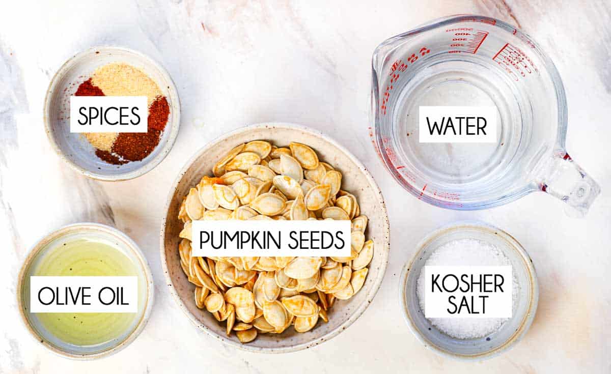 top view of roasted pumpkin seeds ingredients: pumpkin seeds, water, kosher salt, olive oil, spices